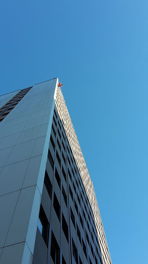 cordiste tout en haut d'un bâtiment blanc