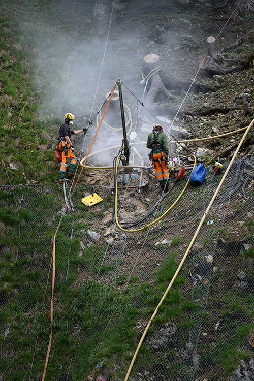  deux travailleurs en train de faire un forage dans une pente raide